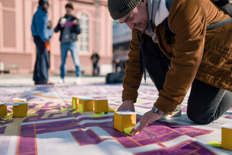 Ein Bürger klebt eine Idee auf einen kleinen gelben Würfel